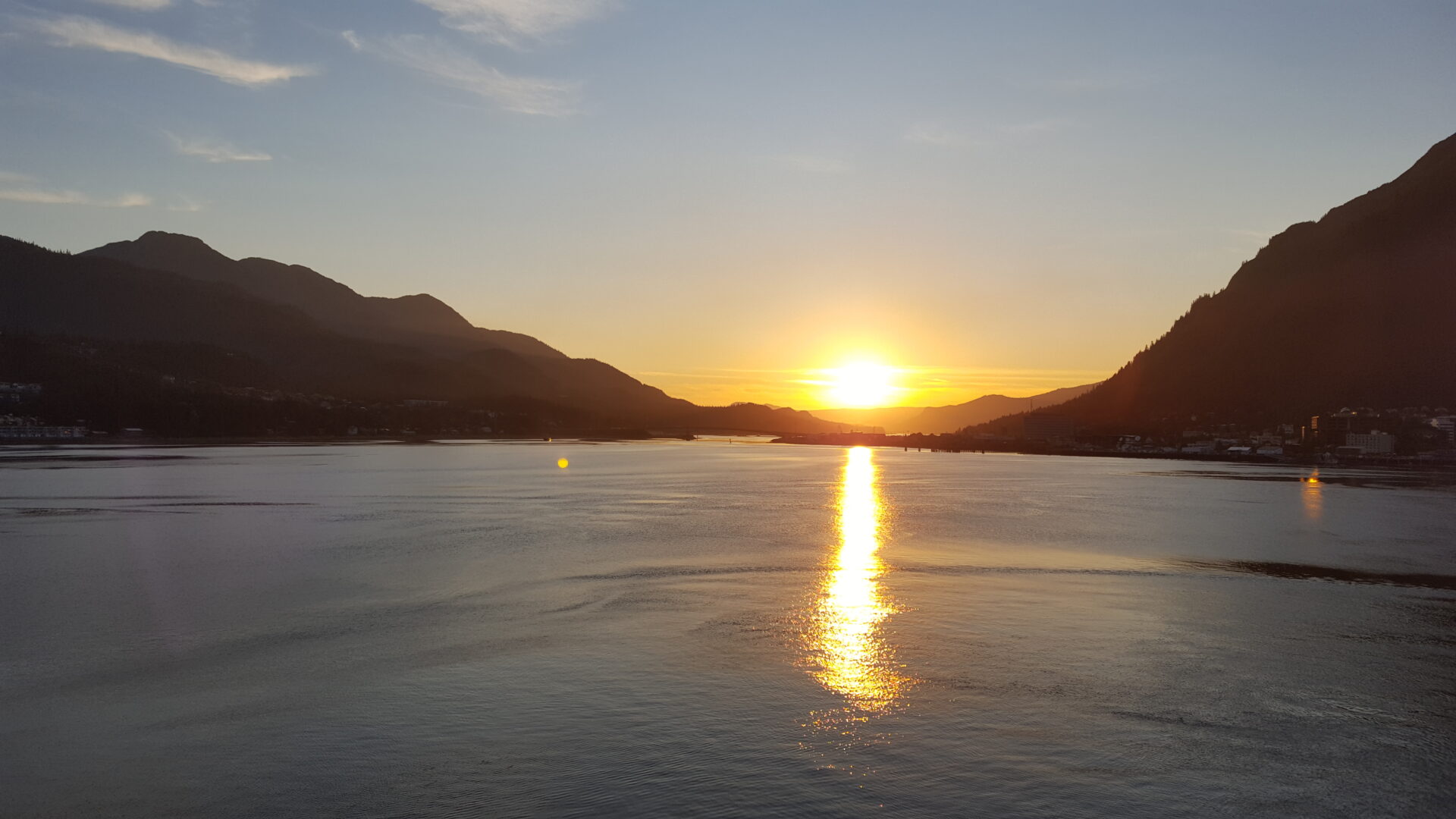 Sunset over calm lake with mountains.