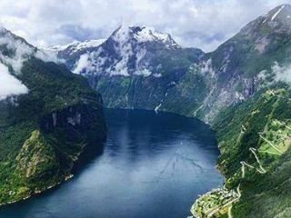 Scenic fjord with mountains and cloudy sky.