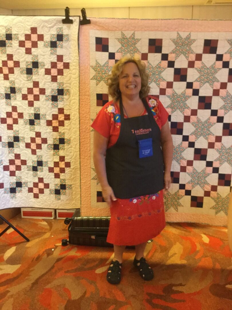 Woman standing in front of two quilts.
