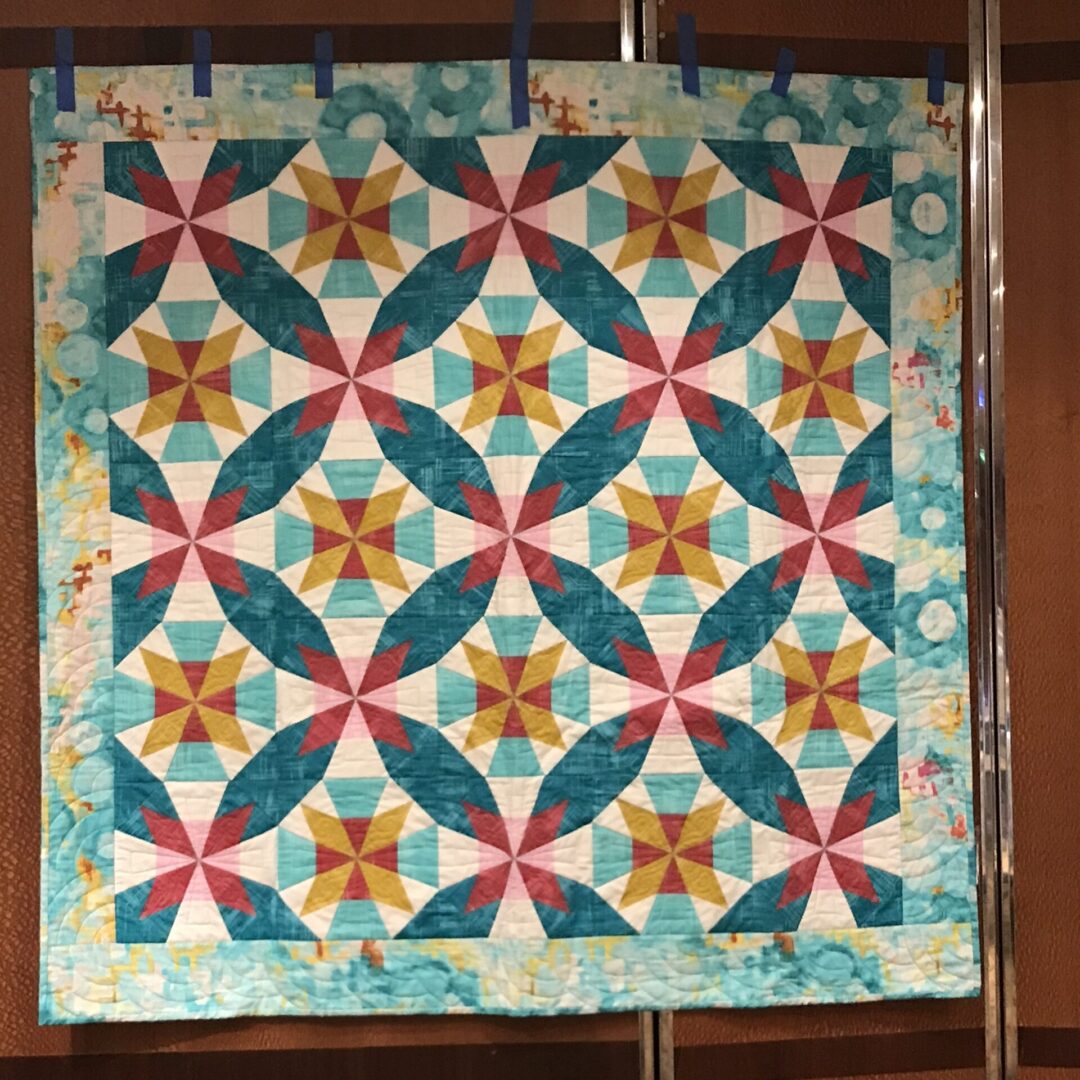 Colorful geometric pattern quilt on display.