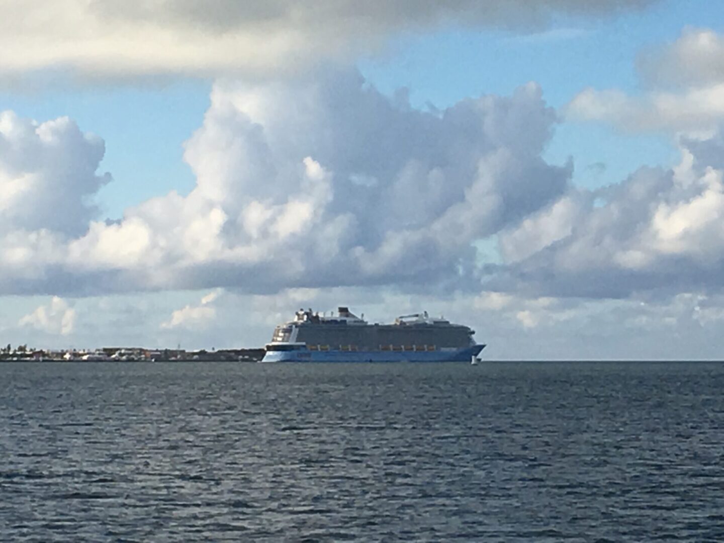 Cruise ship on calm ocean under clouds.