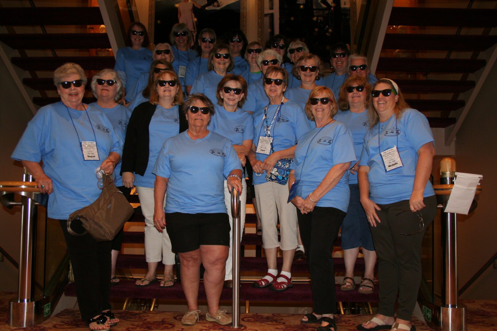 Group wearing sunglasses and blue shirts indoors.