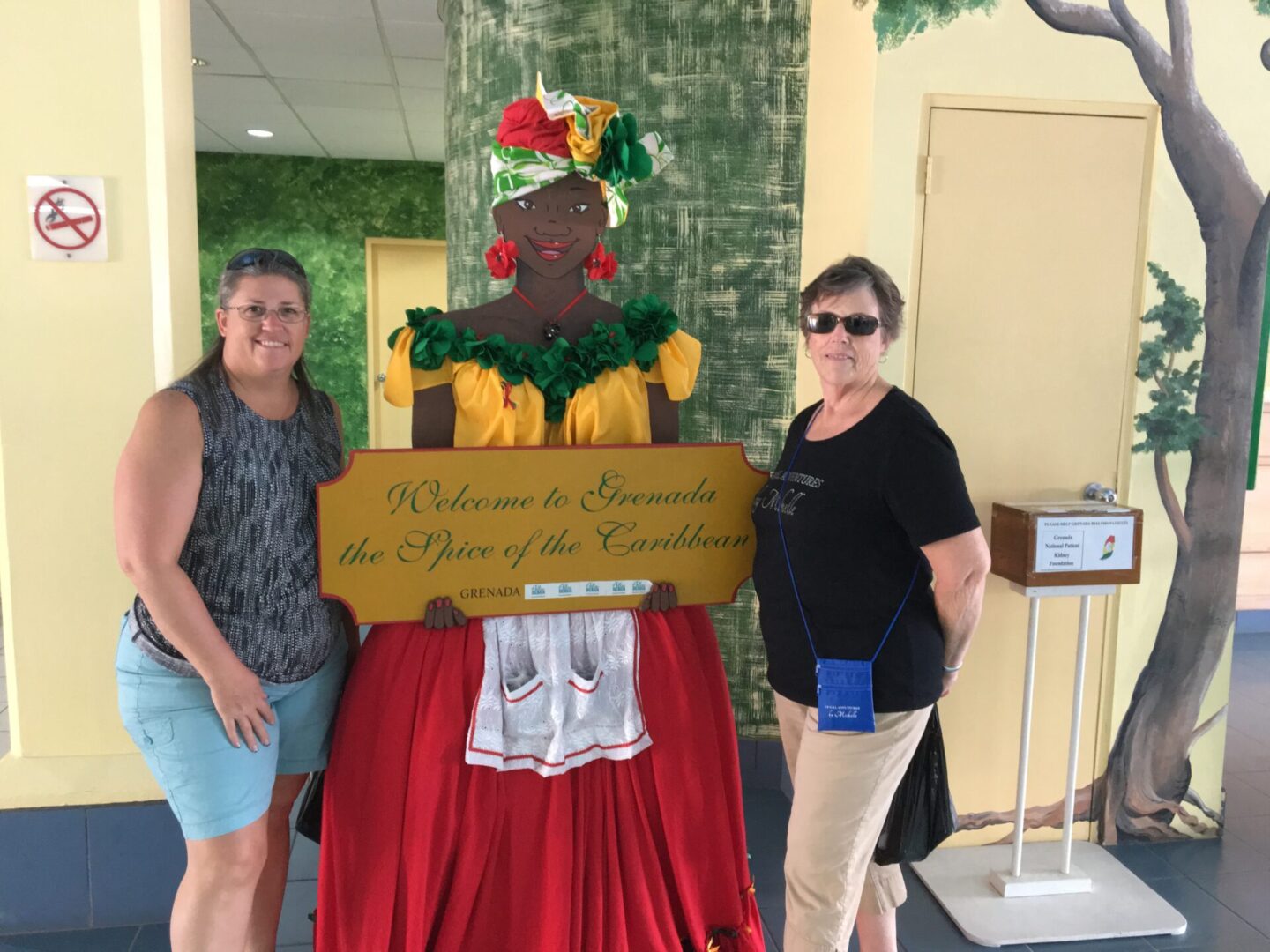 Two women with Grenada welcome sign.