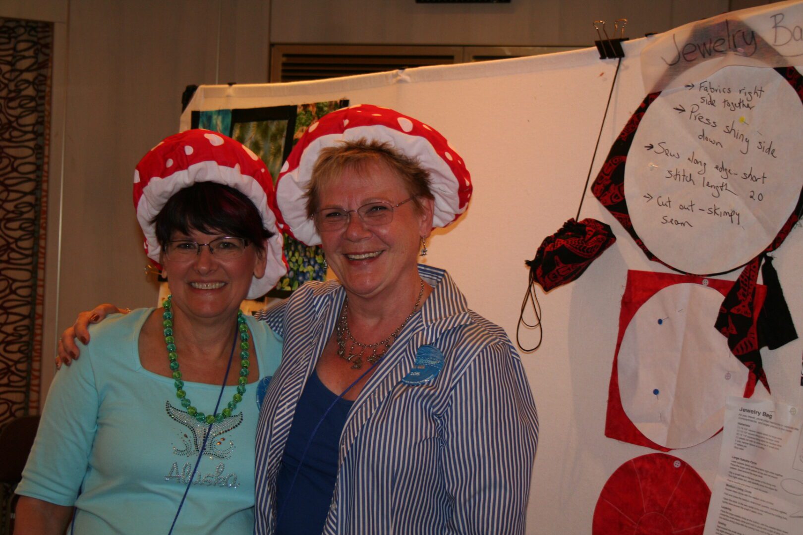 Two women wearing red mushroom hats smiling.