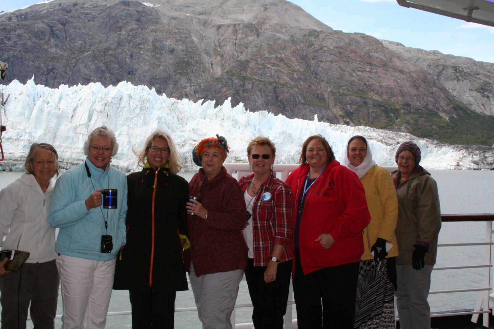 Group of people smiling in front of glacier.
