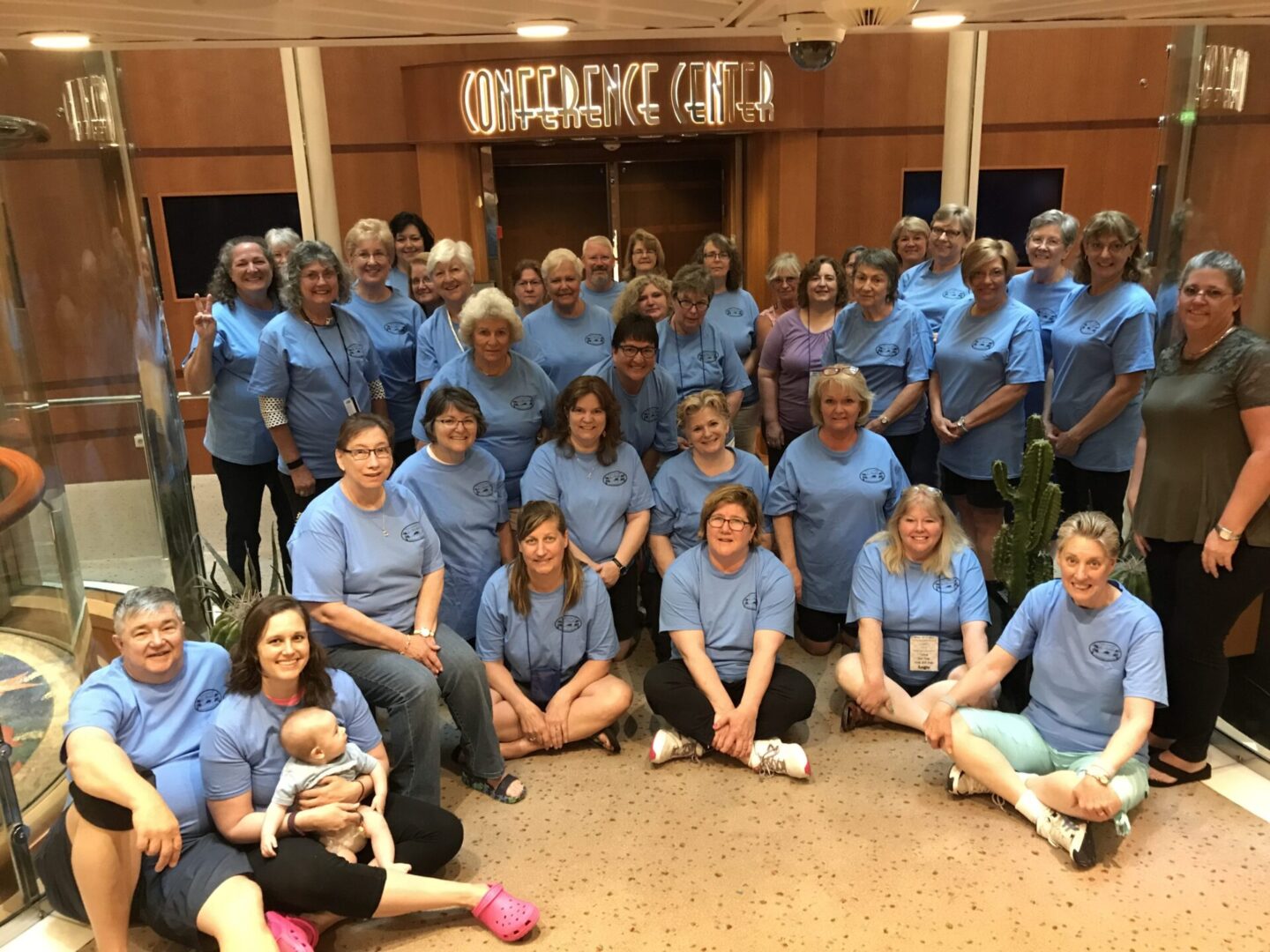Group photo in blue shirts, indoors.