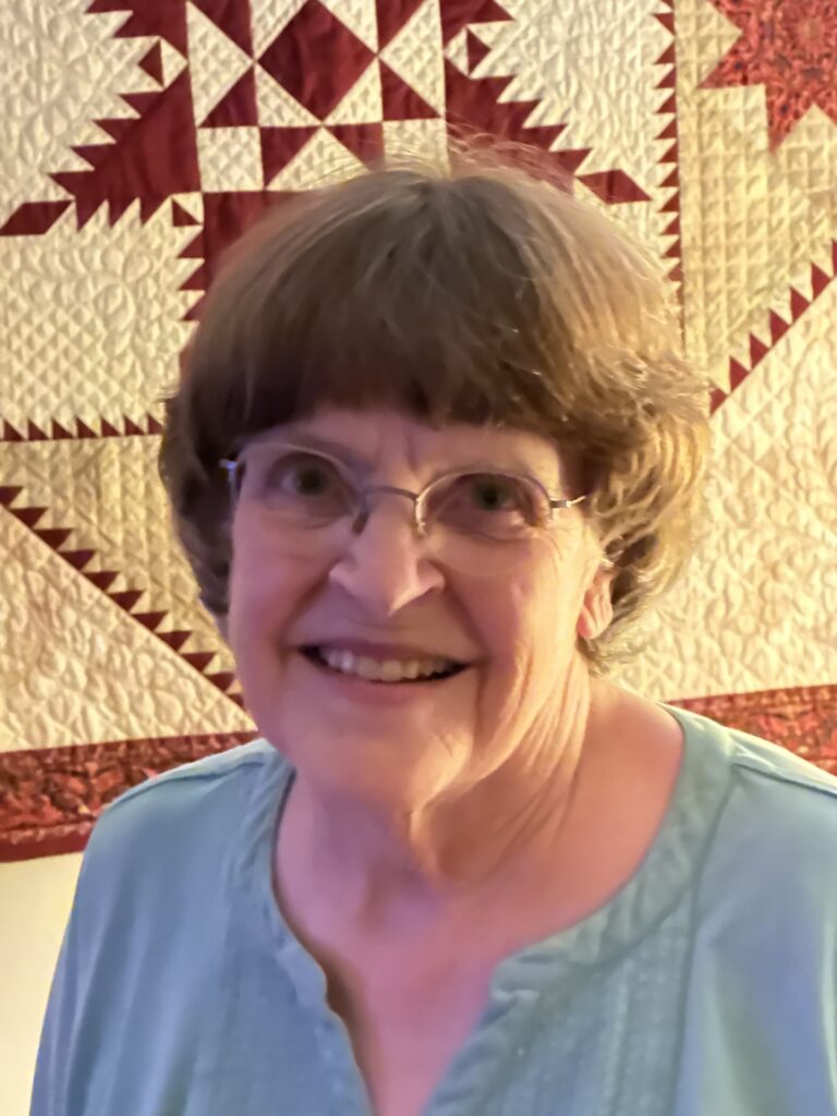 Smiling woman with short hair and glasses.