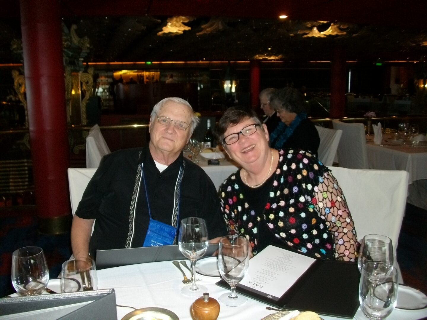 Elderly couple smiling at restaurant table.
